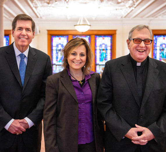 Una mujer con birreta y túnica de graduación sonríe a la cámara